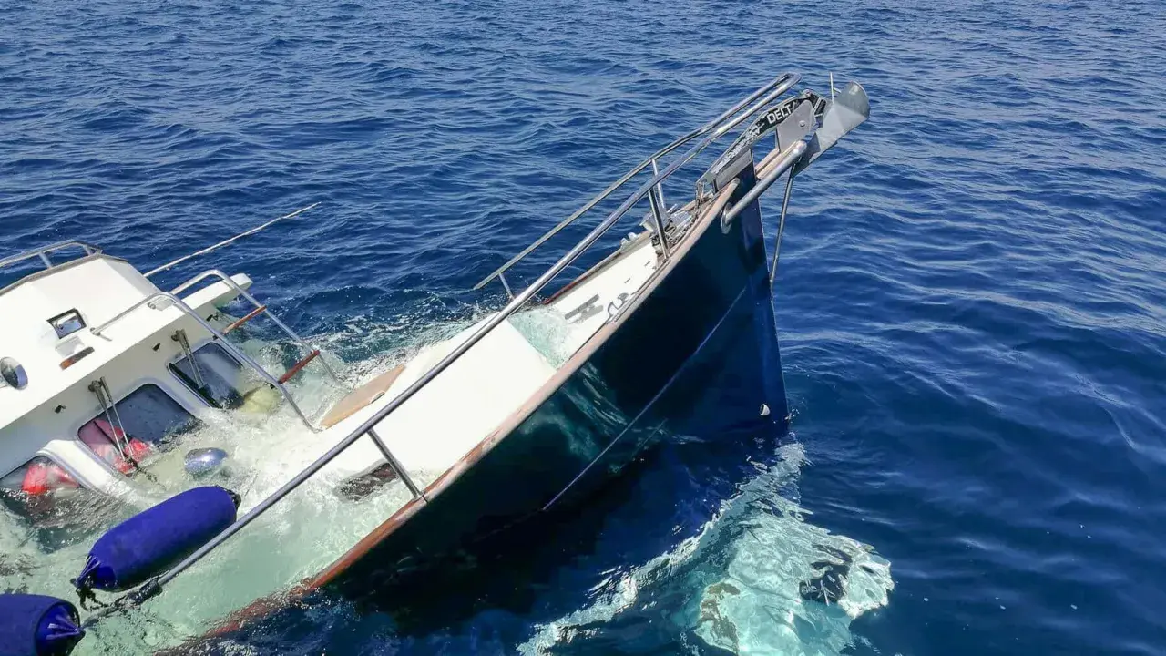 Ein **bilge boot** sinkt im tiefblauen Meer. Rettungsringe und Fender treiben im Wasser.