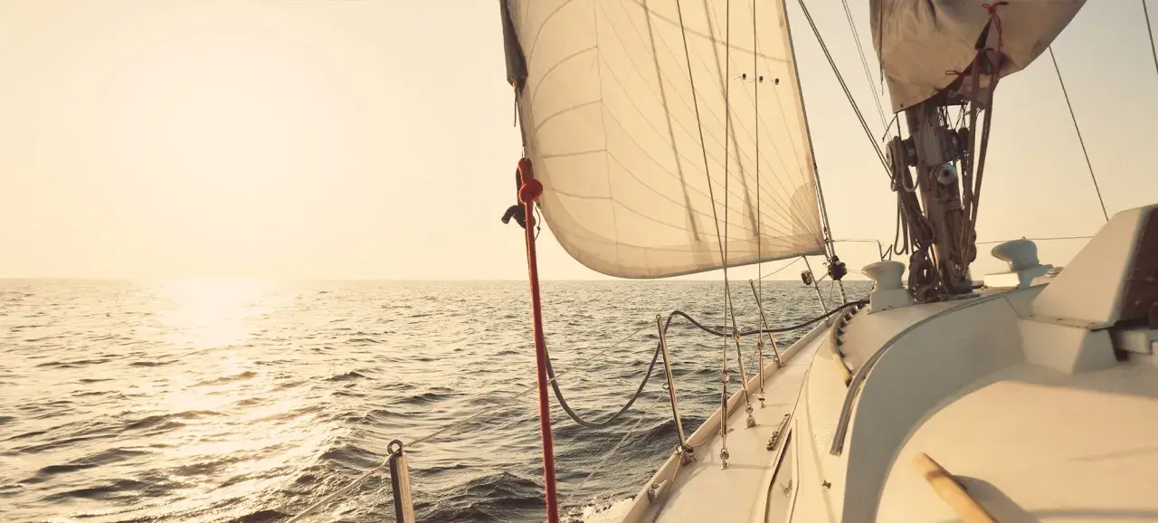 Segelboot gleitet über ruhige See im Sonnenuntergang. Die Segel sind straff gespannt, bereit für die nächste Etappe. Ein Moment der Ruhe vor dem **ausbessern der Segel** für die nächste Reise.