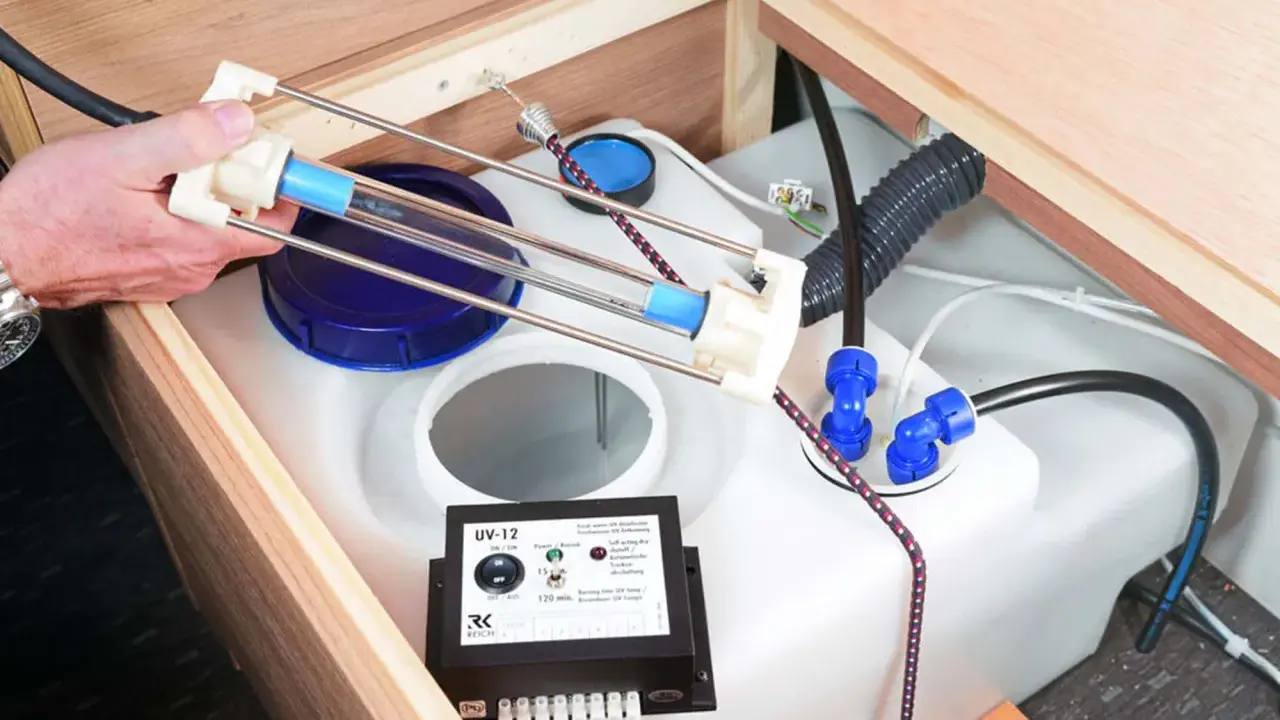 Ein Gerät zur UV-Wasserdesinfektion hilft, das Wasser frisch zu halten. Eine Hand hält eine UV-Lampe über einem Wassertank.