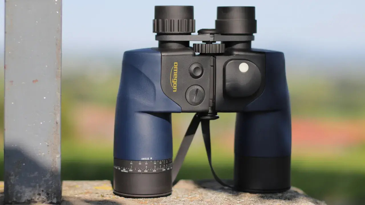 Ein blaues Omegon Fernglas 7x50, dessen Bedeutung in der Vergrößerung und Objektivgröße liegt, steht auf einem Stein.
