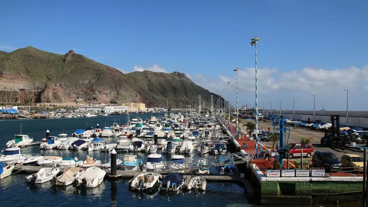 Viele Boote liegen im Hafen von Teneriffa vor Anker, im Hintergrund erheben sich grüne Berge.