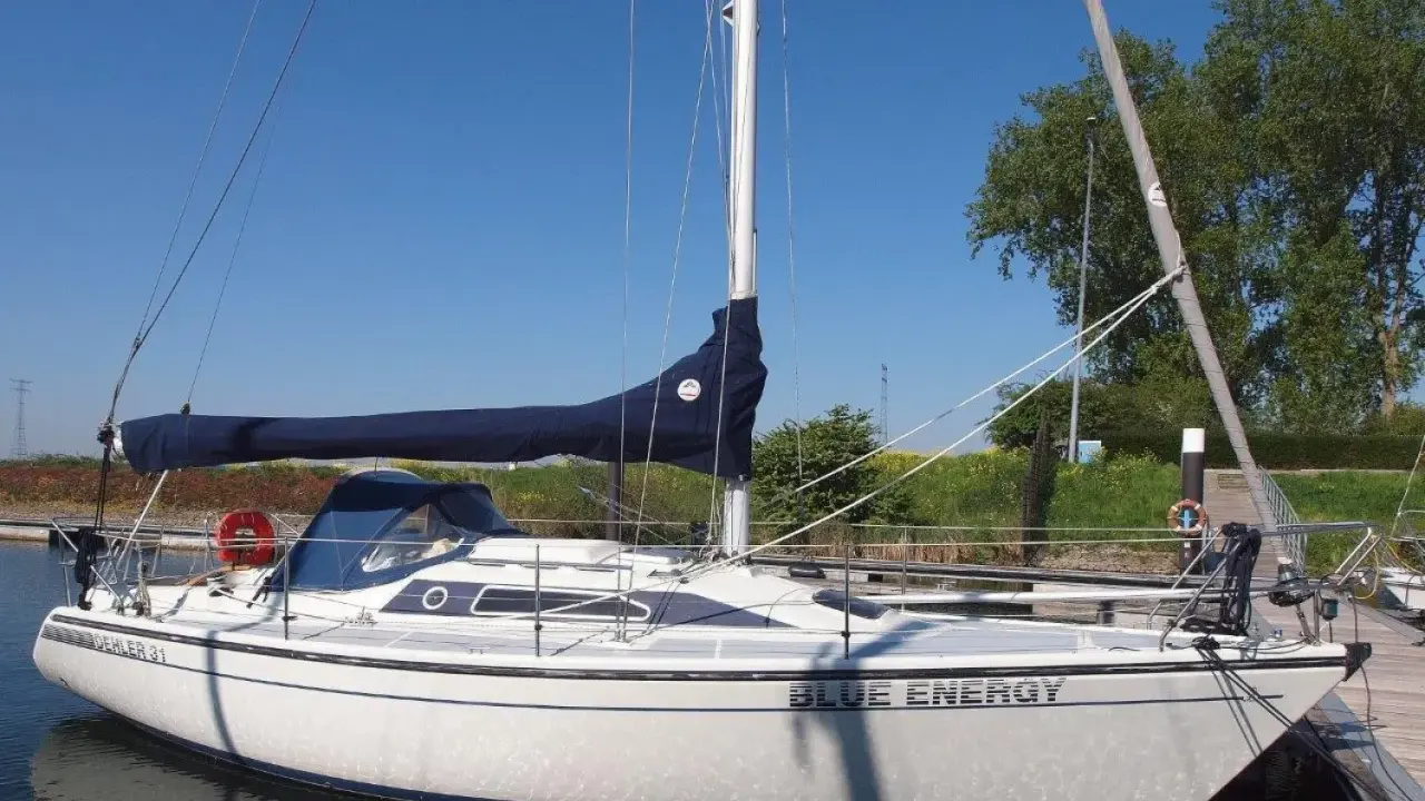Weiße Segelyacht "Blue Energy" mit blauem Segel, liegend am Steg. Interessante dehler 31 technische daten für Segelfreunde.