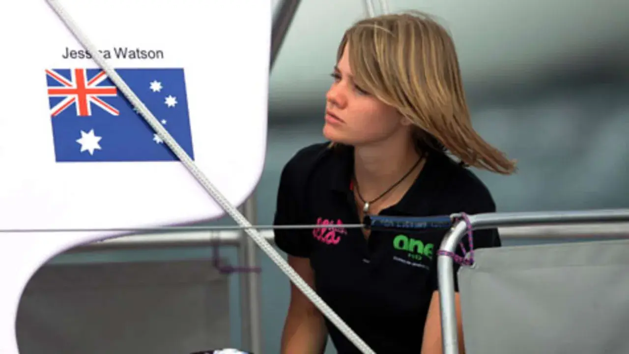 Jessica Watson heute, blickt nachdenklich auf dem Boot. Die australische Flagge ist im Hintergrund zu sehen.