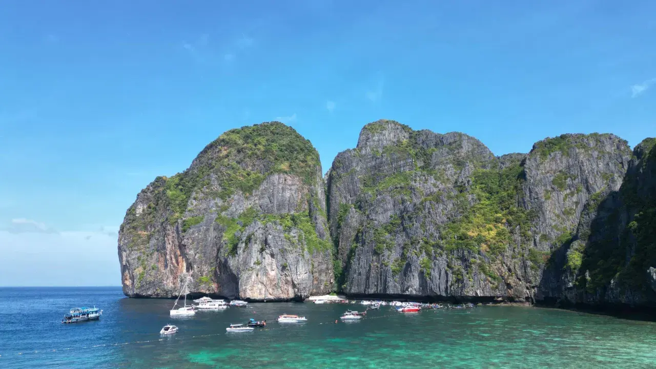 Traumhafte Felsformationen und türkisfarbenes Wasser laden zum Segeln in Thailand ein. Boote ankern in der Bucht.