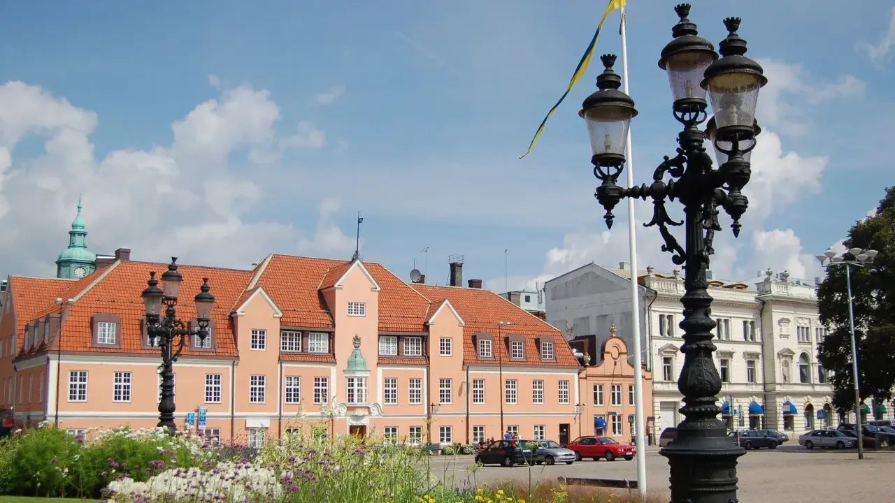 Blumen blühen am Karlskrona Hafen. Ein prächtiges Gebäude mit orangem Dach und eine schwedische Flagge im Wind.
