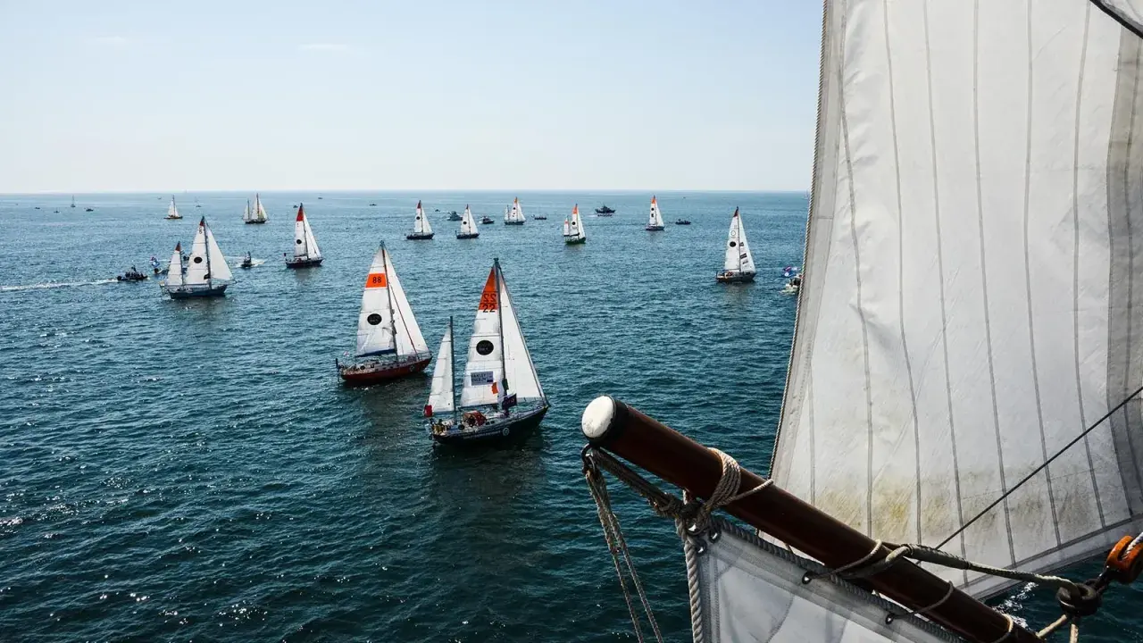 Viele Segelboote auf dem Meer, ein Teil der Segel im Vordergrund. Ein spannender Moment der Golden Globe Race.