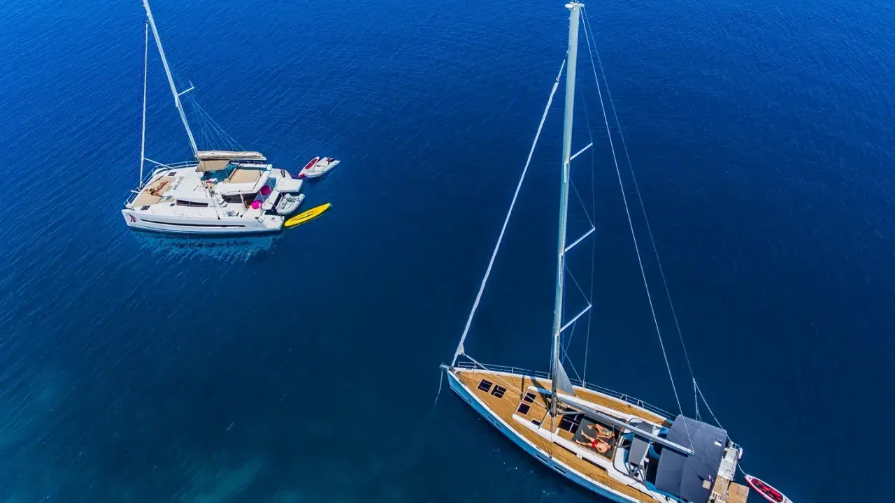 Zwei Segelboote, ein Katamaran und eine Yacht, liegen friedlich auf dem tiefblauen Meer.