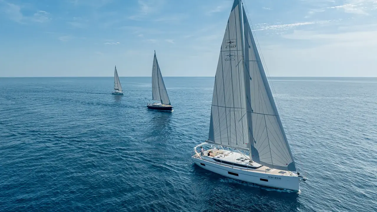 Drei weiße Segelboote segeln auf dem blauen Meer. Die Kosten für ein Segelboot wie dieses sind hoch, aber das Erlebnis unbezahlbar.