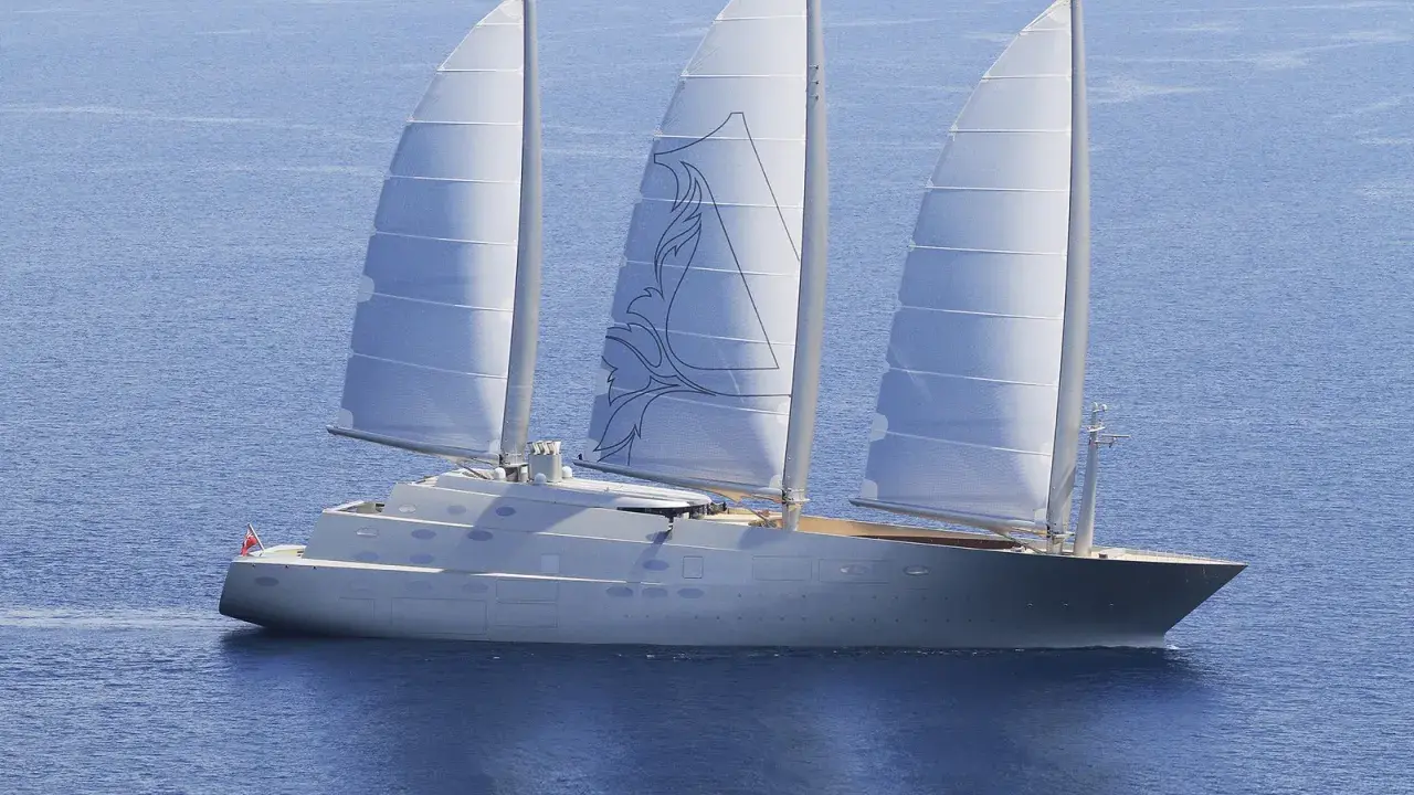 Ein elegantes Segelschiff mit drei Masten gleitet über das blaue Meer. Die Segel sind mit einem stilisierten Muster verziert, das an eine **sy**mbolische Darstellung erinnert.