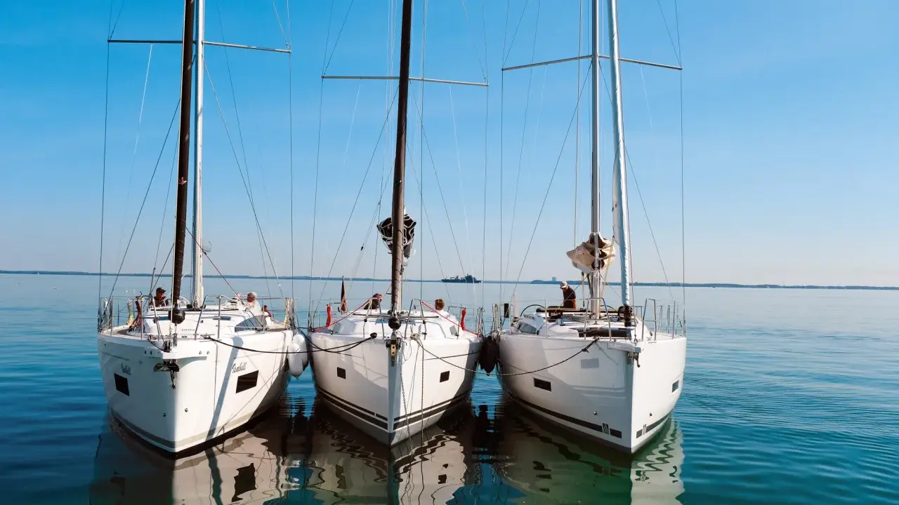 Drei weiße Segelyachten liegen nebeneinander im ruhigen Wasser. Ein Blick auf die elegante Bauweise, wie sie nur ein renommierter segelyacht hersteller hervorbringen kann.