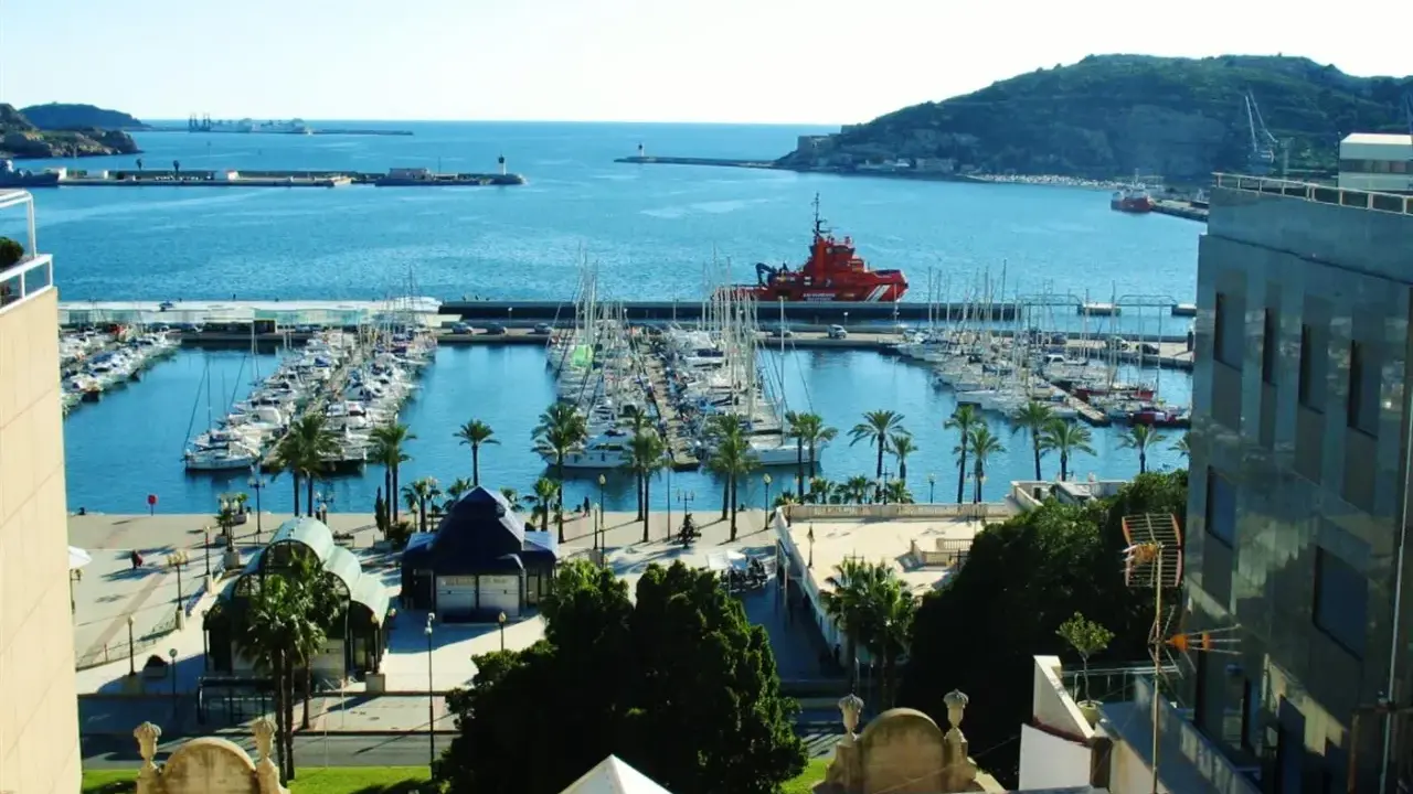 Der Cartagena Hafen mit vielen Segelbooten und einem roten Rettungsboot. Palmen säumen die Promenade.