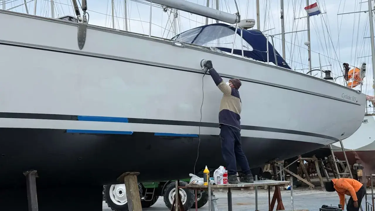 Mann poliert mit Schleifmaschine die Yacht. Edelstahl-Teile glänzen nach der Arbeit.