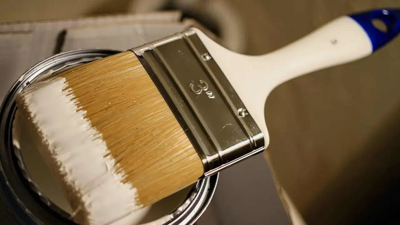 Pinsel mit weißer Farbe, bereit, ein Holzboot zu lackieren.