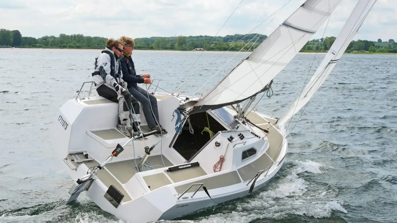 Zwei Segler genießen eine Fahrt auf einer Sailart 20. Das Boot gleitet durch das Wasser, die Segel sind gesetzt.