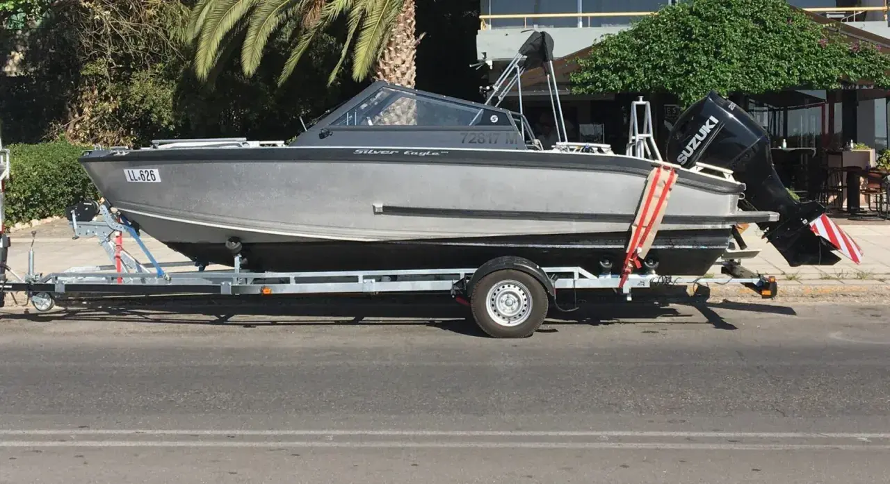 Ein graues Boot, "Silver Eagle", wird auf einem Anhänger transportiert. Der Suzuki Außenbordmotor ist montiert.