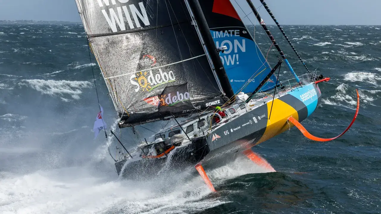 Ein Segelboot kämpft sich durch hohe Wellen, ein Teilnehmer der Segelregatta um die Welt.