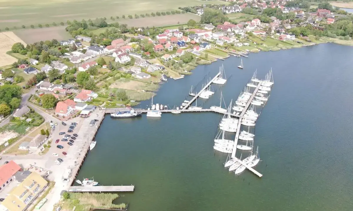 Breege Hafen: Viele Segelboote liegen im Hafen von Breege, umgeben von Häusern und grünen Feldern.