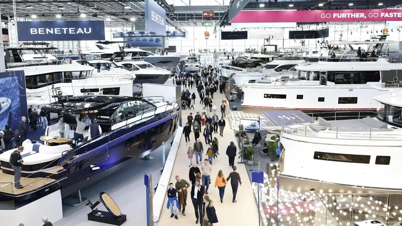Besucher bestaunen Yachten auf einer Messe. Ein glänzendes, blaues Boot im Vordergrund erinnert an eine Fahrt auf dem kanal frankreich.