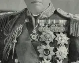 John Fisher trägt eine prunkvolle Uniform mit vielen Orden und Auszeichnungen.
