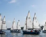 Segelboote mit weißen Segeln und Nummern wie "21" und "K9" auf dem Wasser, ein Teil der Veranstaltung "wm kiel".