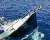 Ein **bilge boot** sinkt im tiefblauen Meer. Rettungsringe und Fender treiben im Wasser.