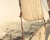 Segelboot gleitet über ruhige See im Sonnenuntergang. Die Segel sind straff gespannt, bereit für die nächste Etappe. Ein Moment der Ruhe vor dem **ausbessern der Segel** für die nächste Reise.