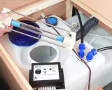 Ein Gerät zur UV-Wasserdesinfektion hilft, das Wasser frisch zu halten. Eine Hand hält eine UV-Lampe über einem Wassertank.