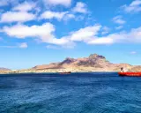 Blick auf die Bucht von Mindelo, Kap Verde, mit Schiffen im tiefblauen Wasser und einer bergigen Küstenlinie im Hintergrund.