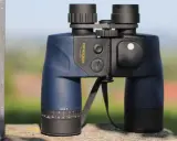 Ein blaues Omegon Fernglas 7x50, dessen Bedeutung in der Vergrößerung und Objektivgröße liegt, steht auf einem Stein.