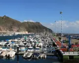 Viele Boote liegen im Hafen von Teneriffa vor Anker, im Hintergrund erheben sich grüne Berge.