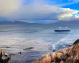 Kreuzfahrtschiff nähert sich Kap Hoorn. Ein kleines Boot fährt voraus.
