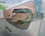 Beschädigte Stelle an einem GFK Boot, bereit für die Reparatur. Die Fasern sind freigelegt, ein Zeichen für notwendige Instandsetzung.