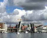 Sonderborg Hafen mit geöffneter Klappbrücke, Segelbooten und Gebäuden unter dramatischem Wolkenhimmel.