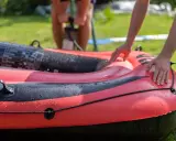 Hände bereiten das Schlauchboot vor, während im Hintergrund jemand pumpt.