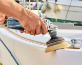 Hand poliert mit Maschine den weißen Bootsrumpf. Glänzende Oberflächen entstehen beim Boot polieren.