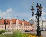 Blumen blühen am Karlskrona Hafen. Ein prächtiges Gebäude mit orangem Dach und eine schwedische Flagge im Wind.