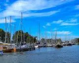 Segelboote im Enkhuizen Hafen unter blauem Himmel mit weißen Wolken.