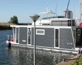 Modernes Hausboot "ULM" im lelystad hafen, umgeben von Schilf und Segelbooten.