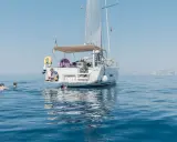 Erfahrungen, wenn du der Crew beitrittst: Ein Mann sitzt auf einer Yacht, während andere im Meer schwimmen.