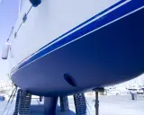 Der blaue **segelboot rumpf** mit weißen Streifen ruht auf Stützen im Hafen.