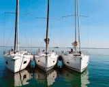 Drei weiße Segelyachten liegen nebeneinander im ruhigen Wasser. Ein Blick auf die elegante Bauweise, wie sie nur ein renommierter segelyacht hersteller hervorbringen kann.