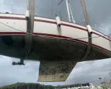 Segelboot wird angehoben, der Rumpf ist mit Algen bedeckt und bereit für die Behandlung mit Epoxidharz zum Streichen.