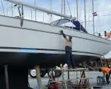 Mann poliert mit Schleifmaschine die Yacht. Edelstahl-Teile glänzen nach der Arbeit.