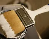 Pinsel mit weißer Farbe, bereit, ein Holzboot zu lackieren.