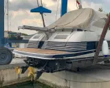 Ein luxuriöses Motorboot wird für das Winterlager aus dem Wasser gehoben. Zwei goldene Propeller ragen aus dem Rumpf.