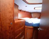 Gemütliches Bett mit gestreifter Bettwäsche im Innenbereich einer Segelyacht. Holzverkleidung und Schränke schaffen eine warme Atmosphäre.
