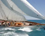 Eine elegante 12mr Yacht gleitet über das türkisfarbene Meer, die weißen Segel strahlen in der Sonne.