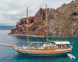 Segelschiff mit vielen Passagieren vor steiler Felsküste, ein Traum für Madeira Segeln.