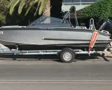 Ein graues Boot, "Silver Eagle", wird auf einem Anhänger transportiert. Der Suzuki Außenbordmotor ist montiert.