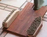 Selbstgebauter Bootsanker aus Holz mit zwei Bürsten und einem grünen Stiefel.